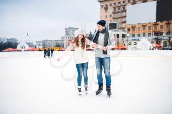 Love couple learn to skate on the rink. Winter skating on open air, active leisure, ice-skating