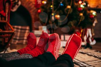 Couple feet in merry red socks, christmas tree with decoration on background, xmas holiday concept