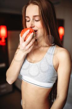 Young woman in underwear eating fresh apple in the morning. Healthy lifestyle, early light breakfast
