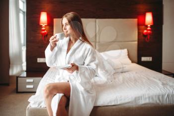 Female person in bathrobe holds in hand a cup of coffee, good morning concept. Healthy lifestyle, light vitamin breakfast