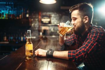 One bearded man drinks beer at the bar counter. Male person leisure in pub