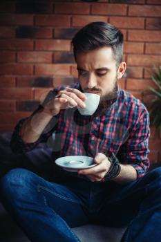 One bearded man drinks coffee in cafe. Male person leisure in pub