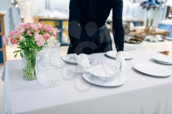 Waitress puts the dishes for banquet, table setting. Serving service, festive dinner decoration, holiday dinnerware