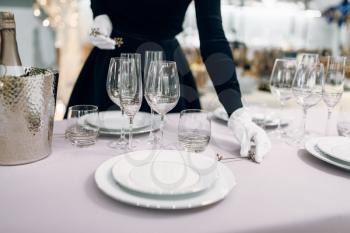 Waitress in gloves puts the knife, table setting. Serving service, festive dinner decoration