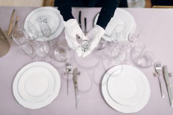 Waitress in gloves puts the dishes, table setting, top view. Serving service, festive dinner decoration, holiday dinnerware
