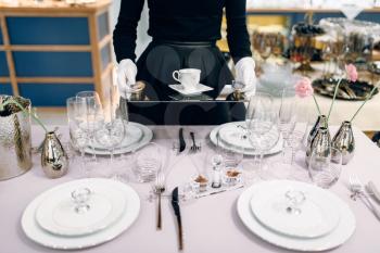 Waitress with a tray puts the dishes, table setting. Serving service, festive dinner decoration, holiday dinnerware