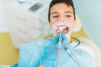 Caries removal procedure, pediatric dentistry. Female dentist drilling teeth, dental clinic