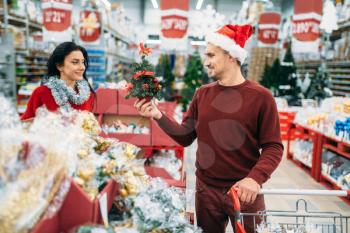 Happy couple buying christmas souvenirs in supermarket, family tradition. December shopping of new year goods