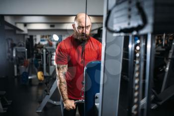 Athletic male person in sportswear, training on exercise machine in gym. Bearded man on workout in sport club, healthy lifestyle