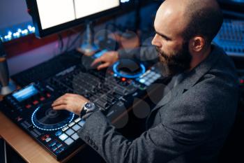 Male sound editor at remote control panel in the recording studio. Musician at the mixer, professional audio mixing