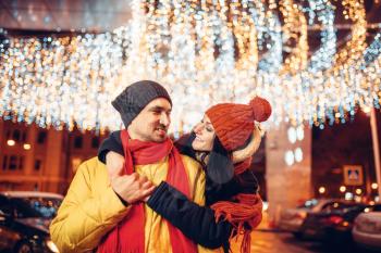 Winter evening, smiling love couple hugs on the street. Man and woman having romantic meeting, happy relationship