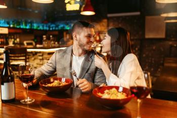 Love couple flirting at wooden bar counter, romantic dinner with paste and red wine. Lovers leisures in pub, husband and wife relaxing together in nightclub