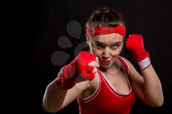 Female boxer in red gloves and sportswear on boxing workout. Woman fighter on black background