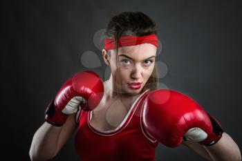 Female boxer in red boxing gloves and sportswear, front view. Fighting sport concept