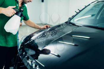 Preparing car, protect against chips and scratches. Worker disperses soapy water. Paint protection. Protective coating