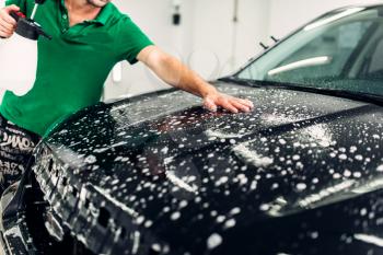 Protect car details against chips and scratches. Worker disperses soapy water on hood. Paint protection. Protective coating