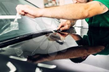 Man installs car paint protection film on hood. Transparent protective coating against chips and scratches