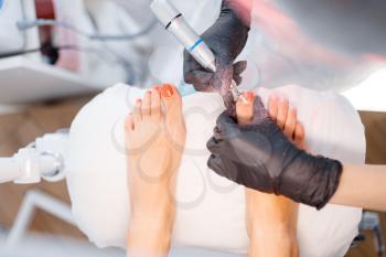 Beautician salon, pedicure, polish procedure. Nail care treatment for female client in beauty shop, doctor in gloves works with customer toenails