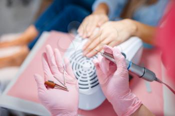 Cosmetology salon, manicure, nails polishing machine. Hands care treatment for female client in beauty shop, woman at the cosmetologist, master works with fingernails