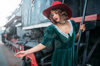Woman in red hat on vintage steam locomotive. Old train. Railway engine, railroad journey 