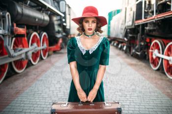 Young old-fashioned woman travels on retro train. Old locomotive. Railway platform, railroad journey