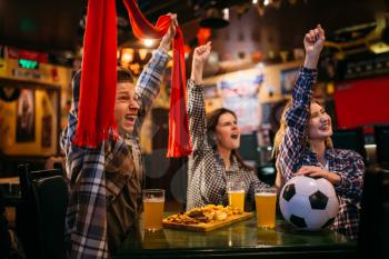 Football fans with scarf watching match and raise their hands up in sports bar. Tv broadcasting, young friends leisures in pub, favorite team wins