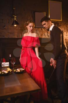 Young love couple in restaurant, romantic date. Elegant woman in red dress and her man dining