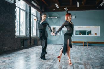 Two dancers in costumes on ballrom dance training in class. Female and male partners on professional pair dancing in studio