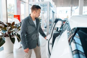 Man buying new car in showroom. Male customer choosing vehicle in dealership, automobile sale, auto purchase