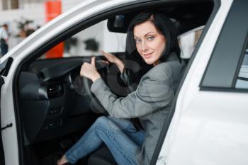 Woman buying new car in showroom, lady behind the wheel. Female customers choosing vehicle in dealership, automobile sale, auto purchase