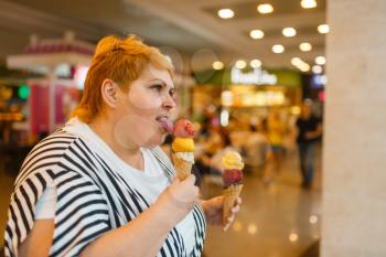 Fat woman eating two ice creams in fastfood mall restaurant. Overweight female person with ice-cream, obesity problem