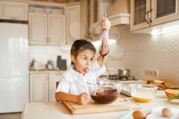 Young kid mixing melted chocolate in a bowl. Cute boy cooking on the kitchen. Happy child prepares sweet dessert