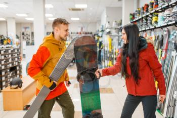 Couple buying downhill ski and snowboard, shopping in sports shop. Winter season extreme lifestyle, active leisure store, customers choosing skiing equipment