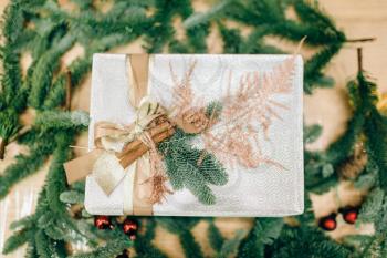 Gift box in wrapping paper and fir branch decoration, top view, nobody. Festive christmas package