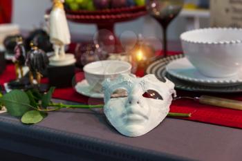 Christmas table decorated with mask, candles and flower closeup, nobody. Holiday celebration