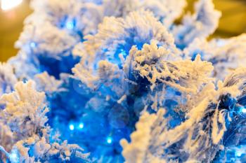 Christmas tree branch with blue decor and lights, garland closeup. Xmas decoration, new year. Winter holiday celebration