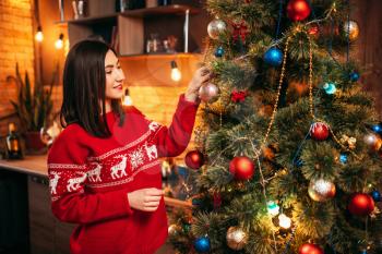 Young woman in red sweater decorate christmas tree. Xmas celebration, home holiday