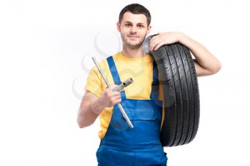 Service worker in blue uniform holds tire in hand, white background, repairman with tyre