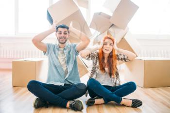 Playful couple sitting on the floor in yoga pose among carton boxes, moving to new house, housewarming. Man and woman have a fun