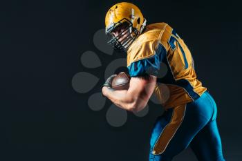 American football offensive player with ball in hand, national league, black background. Contact sport