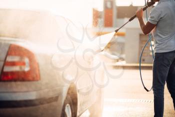 Male worker wash the car with high pressure washer. Car-wash station