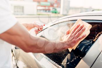 Male hand with tool for washing windows, car wash. Carwash station