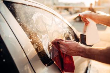 Male hand with tool for washing windows, car wash. Carwash station