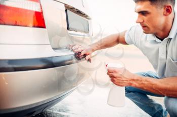 Automobile polishing on car wash station. Man rubbing vehicle bumper with polish. 