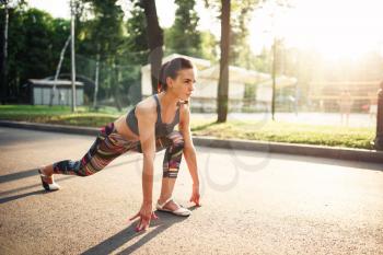 Slim sporty woman doing stretching exercises on morning fitness training in summer park. Athletic girl in sportswear on outdoor fit workout