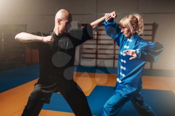 Male and female wushu fighters exercises indoor, martial arts. Sparring partners in action