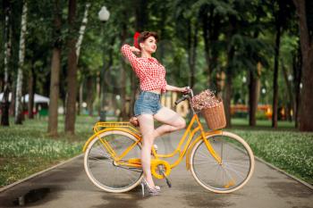 Pin-up girl on retro bicycle, vintage american fashion. Cute woman in pinup style