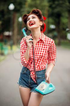 Smiling pinup girl with retro rotary phone, vintage american fashion. Sexy woman in pin up style