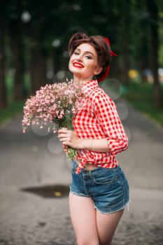 Pinup girl with bouquet of flowers, retro american fashion. Cute smiling woman in pin up style