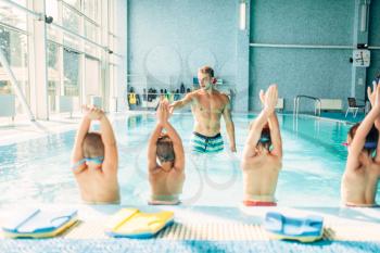 Kids doing exercise in swimming pool with hands up. Instructor shows an exercise for children. Healthy sports activity in pool. Sportive kids activity.